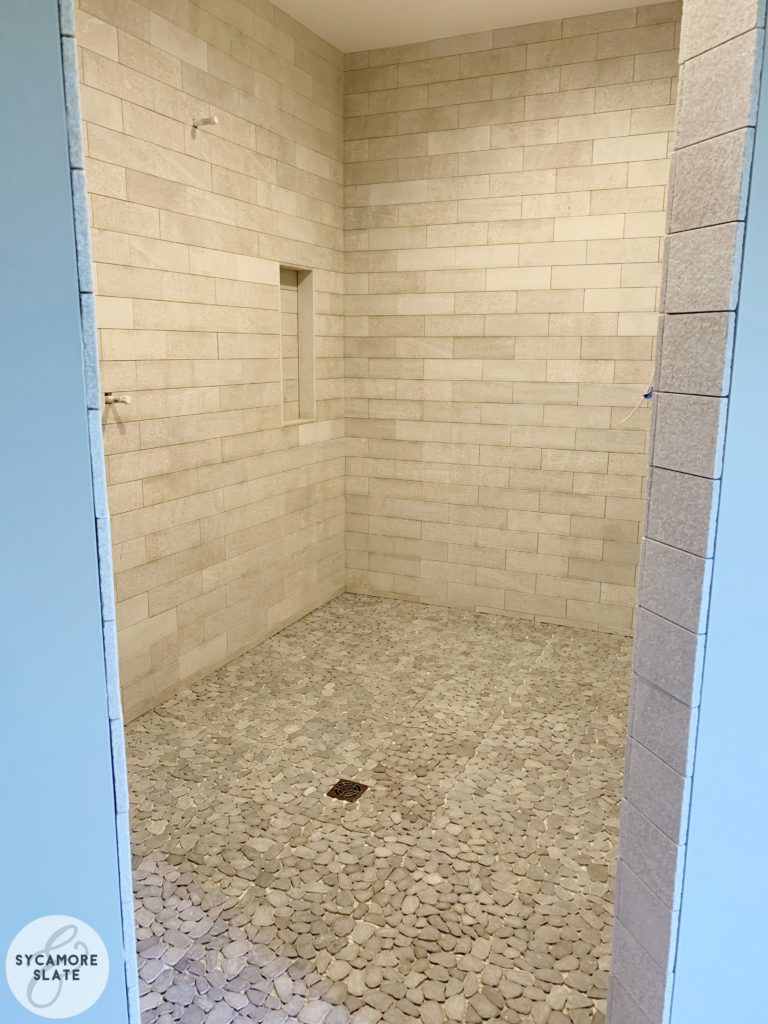 Master Bathroom Walk-in Shower with natural stone subway tile and flat pebble tile on floor